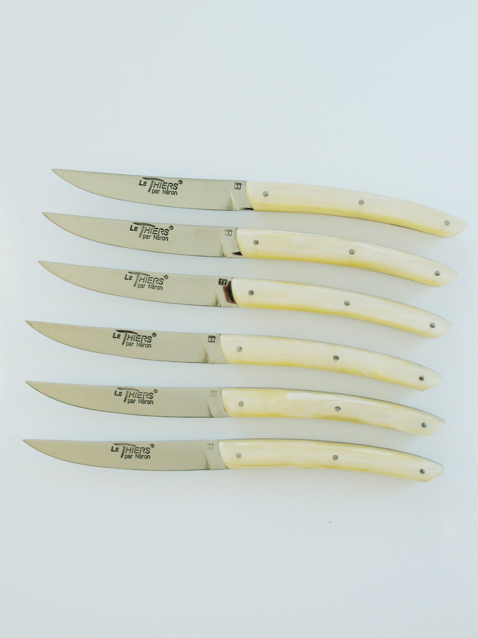 Row of six knives with pearl handles.