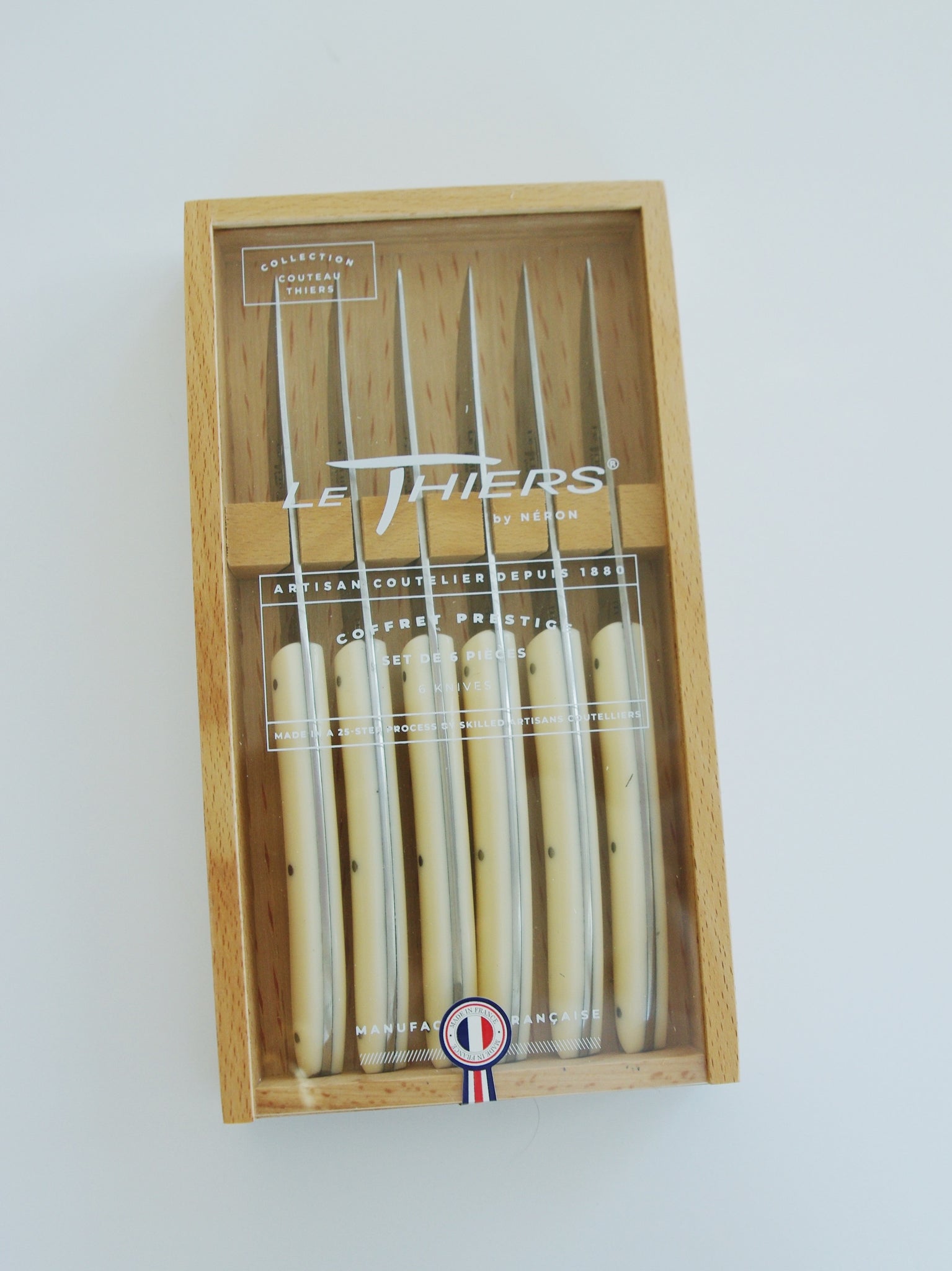 Wooden box of six knives with acrylic lid. French flag sticker reading 'Made in France' in French. Sticker reads Collection Couteau Thiers.