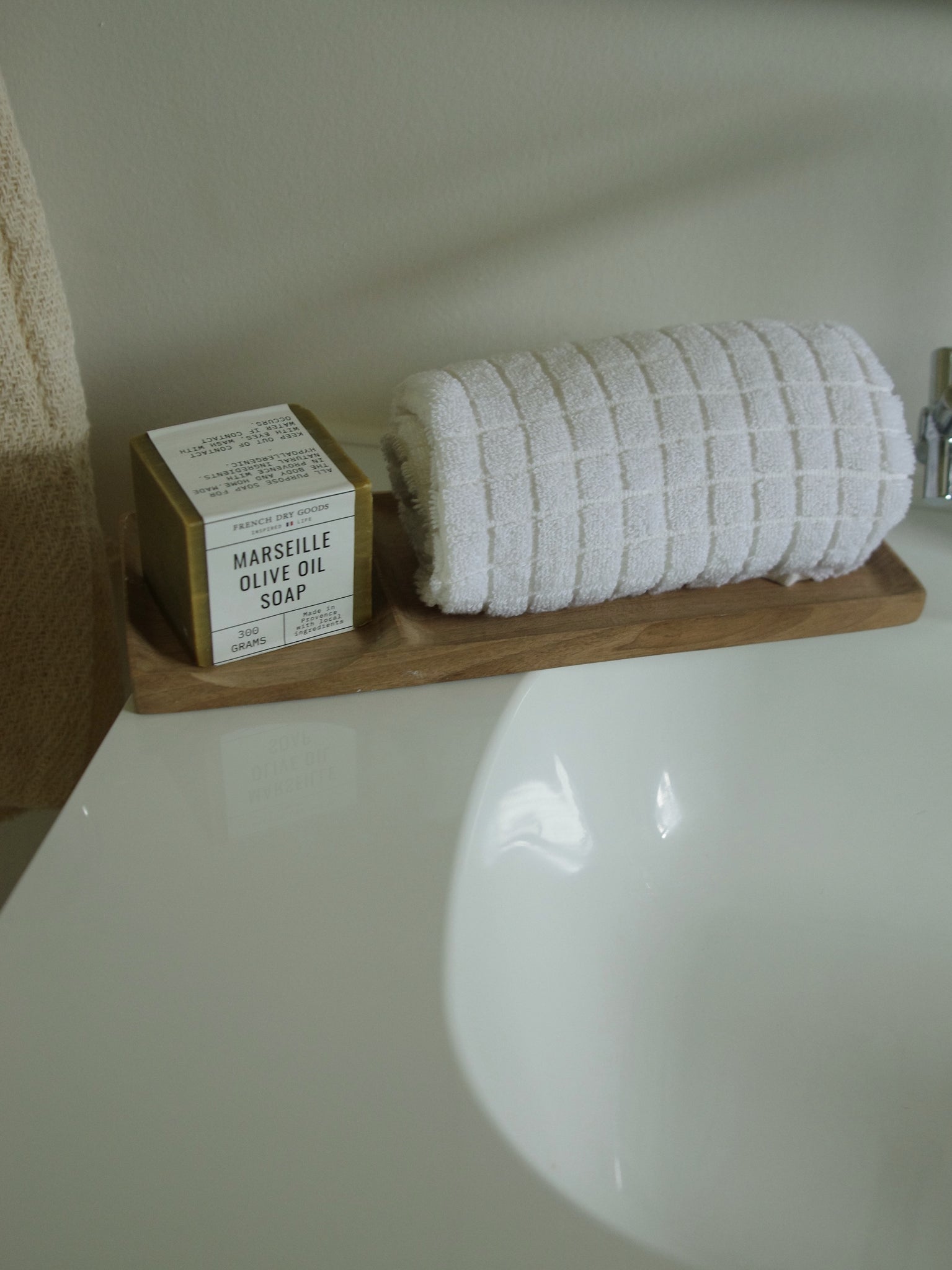 Wooden bathroom tray holding soap and folded towel.