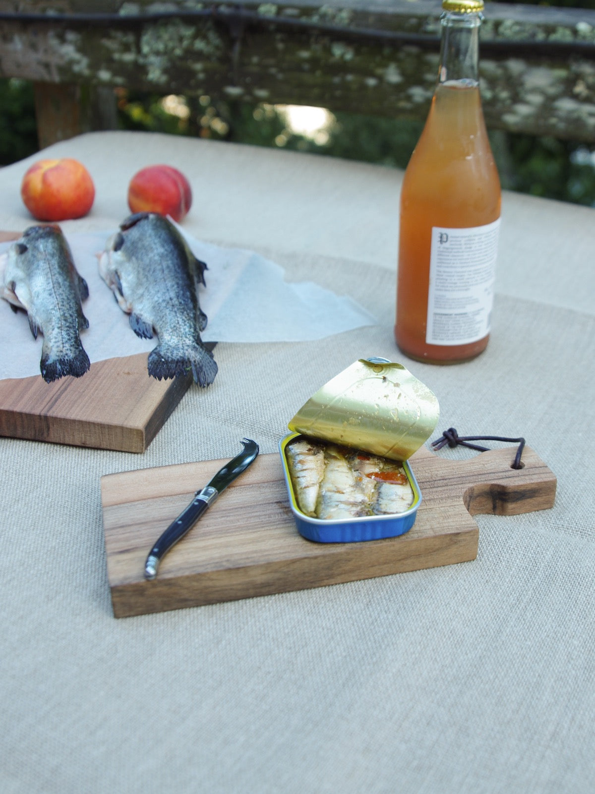 Small wooden cutting boards with sardines and knife on top.