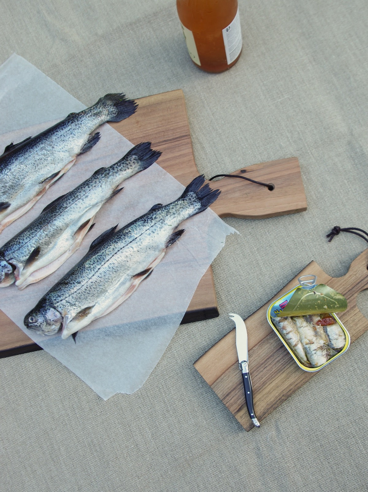 Sardines and fish on two wooden cutting boards with handles.