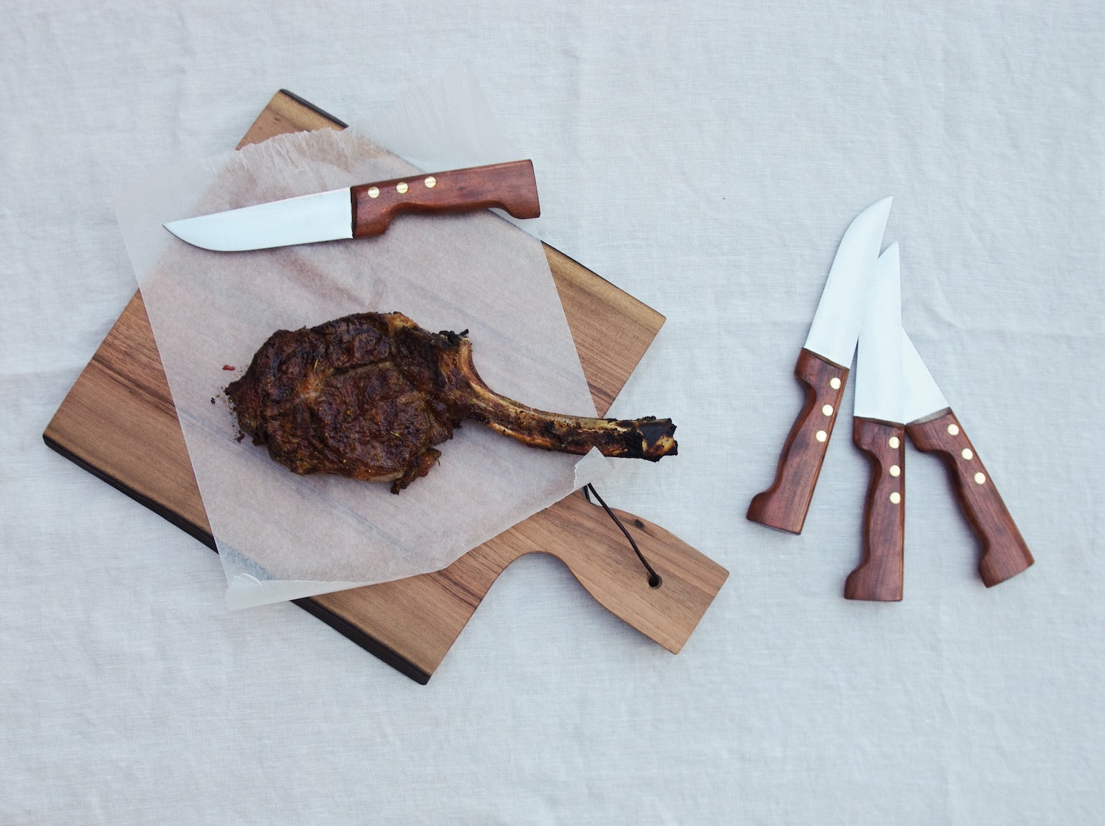Knife and cooked meat on wooden cutting board.