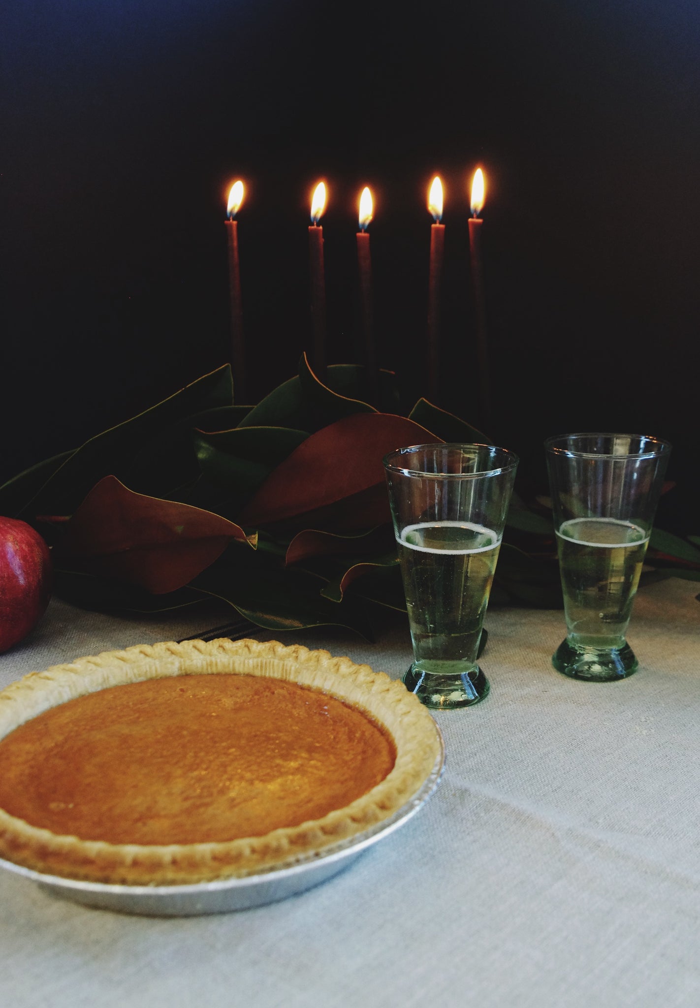 Two small green glasses with champagne in them next to a pie.
