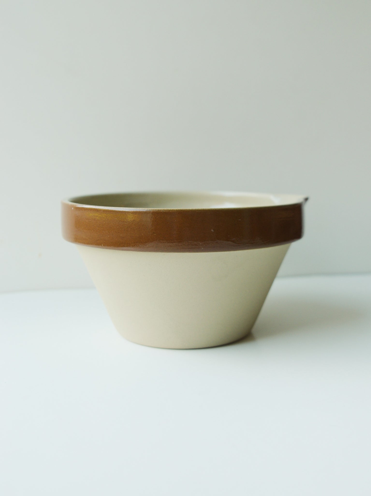 Vintage French mixing bowl with small pour spout. Brown thick rim around top and cream base.