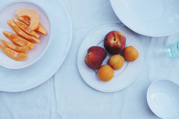 Ceramic plates and bowls holding cut fruit.