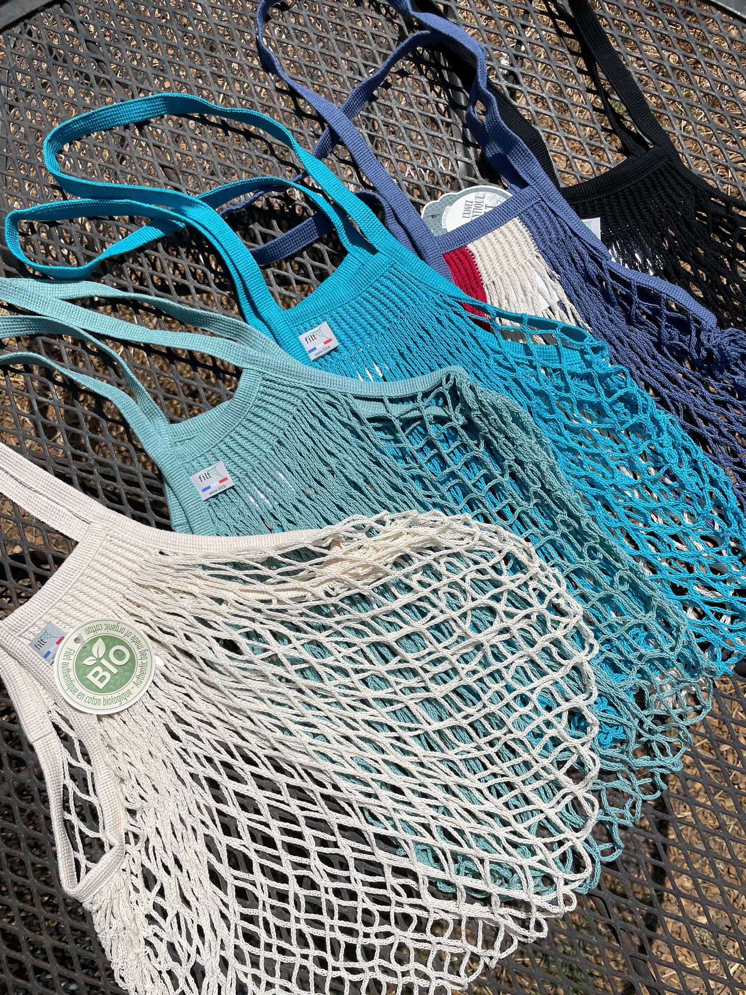 5 net shopping bags in different colors: beige, aqua, teal, red/white/blue, black.