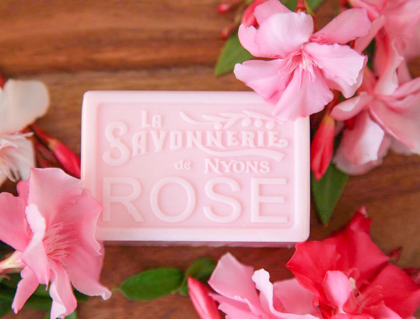 Bar of pink soap that reads La Savonnerie de Nyons Rose surrounded by pink flowers.