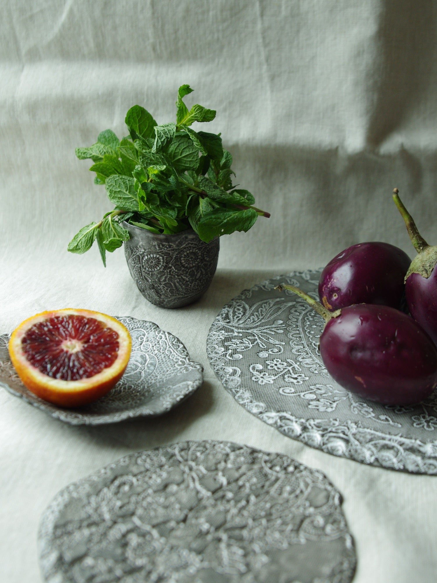Table setting of lace pattern ceramic serveware with fruits and vegetables