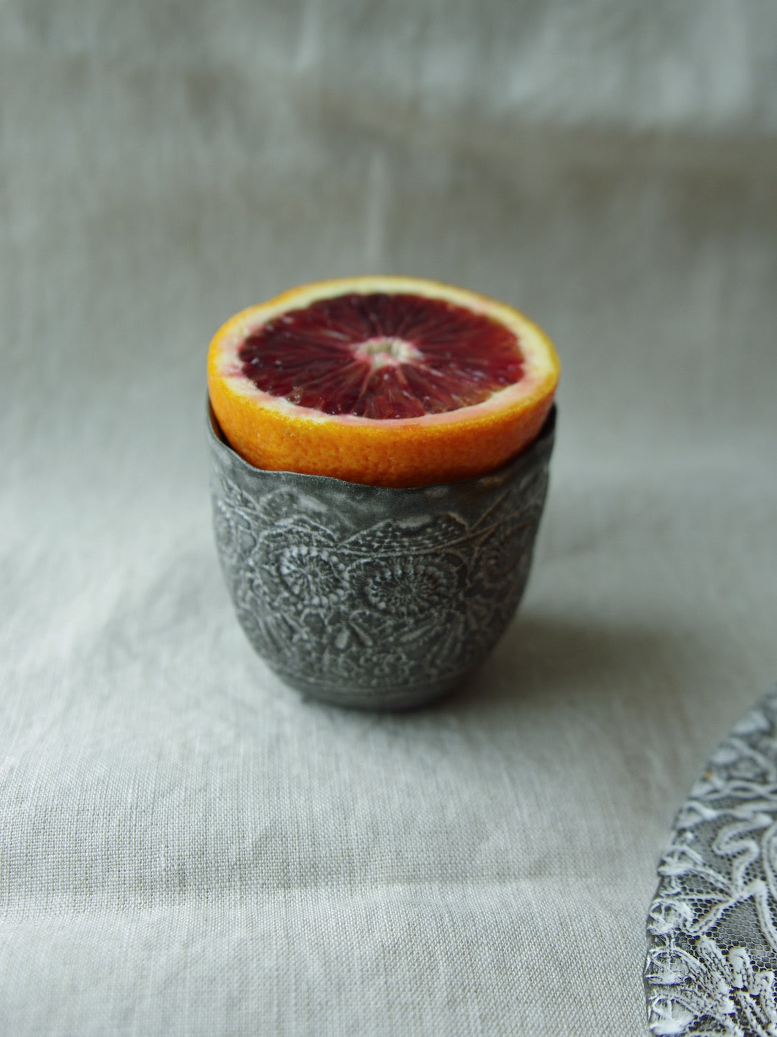 Grapefruit slice sitting atop lace pattern ceramic cup